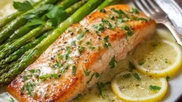 Saumon cuit au four dans du papier d'aluminium avec des asperges et une sauce au beurre à l'ail et au citron